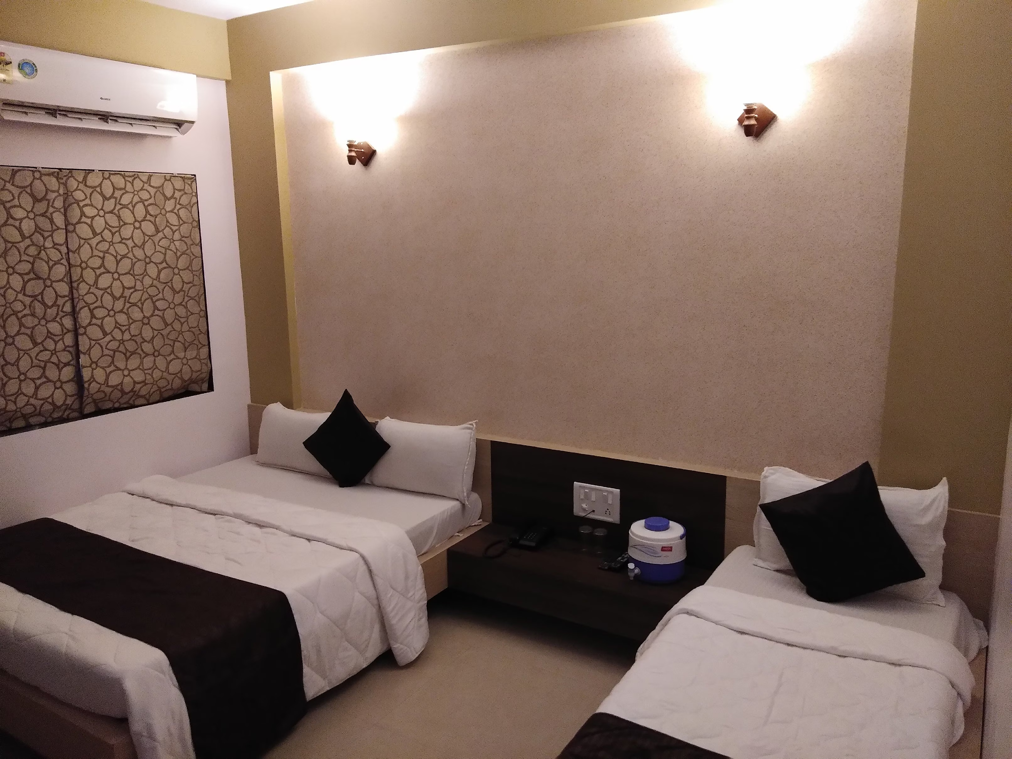 Comfortable sleeping arrangements in Hotel Somnath Atithigruh's triple bed room, showing three individual beds and tidy setup.